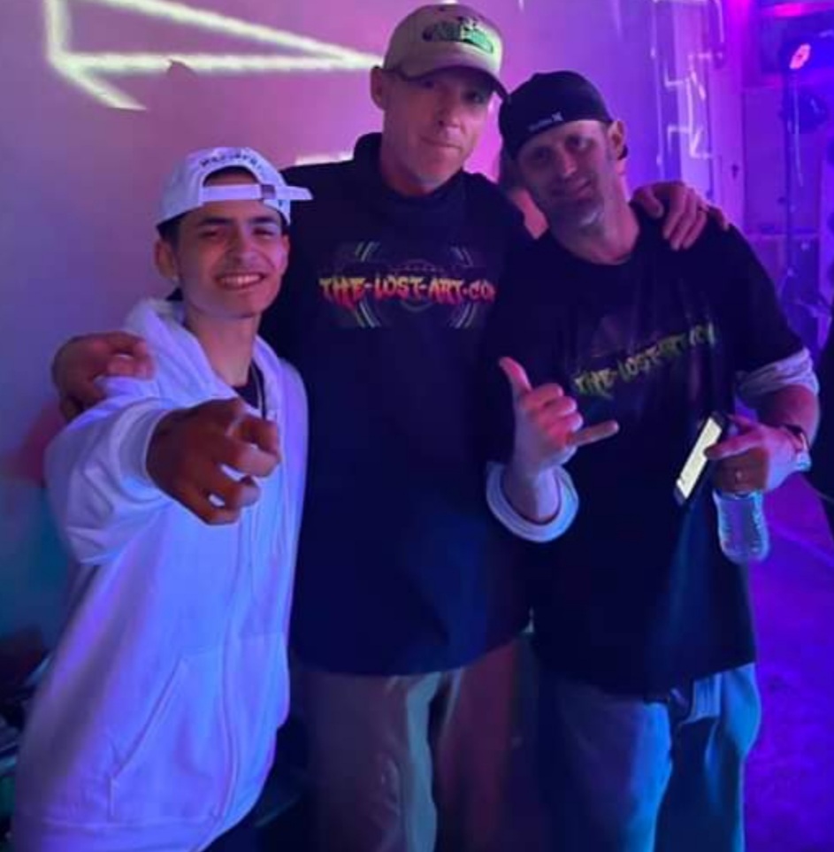 DJ Natural Nate® with two crew members in The-Lost-Art™ Co shirts under purple light